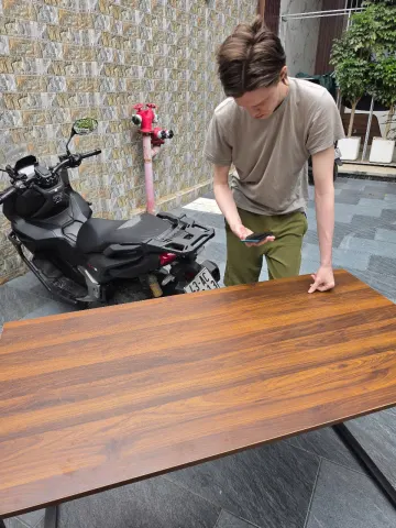 Khách hàng kiểm tra mặt bàn gỗ tại cửa hàng